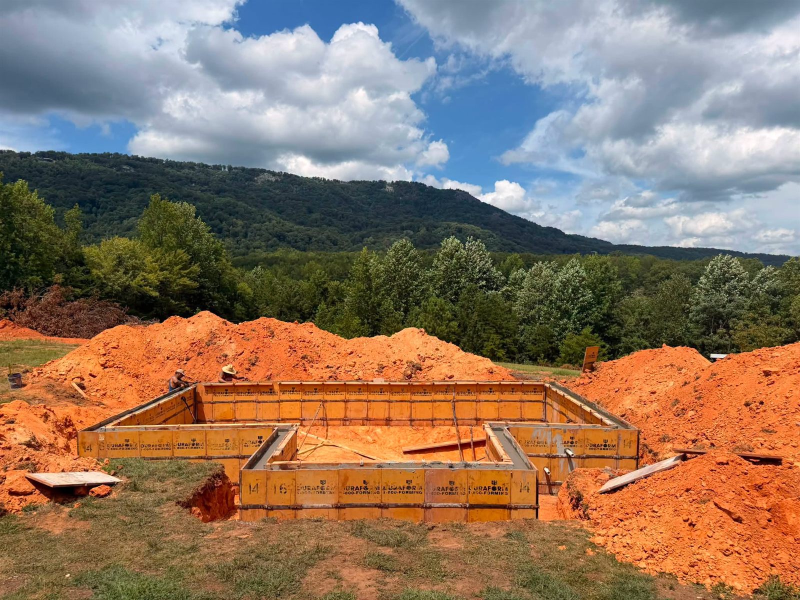 Glassy Mountain Pools crew setting wall forms on a new build with a mountain ridge behind