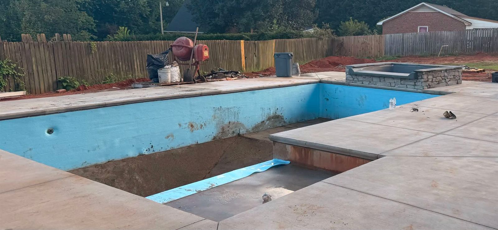 Older in-ground pool stripped for a liner replacement with the floor re-prepped and new liner rolled out