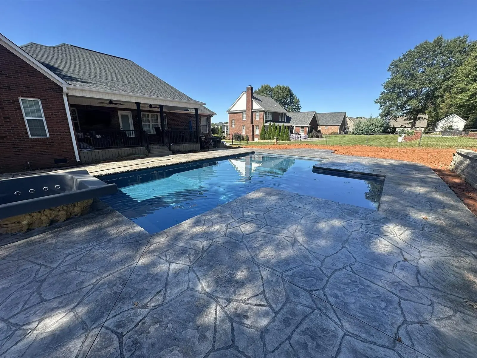 Custom in-ground pool with stone retaining wall and mountain views at dusk
