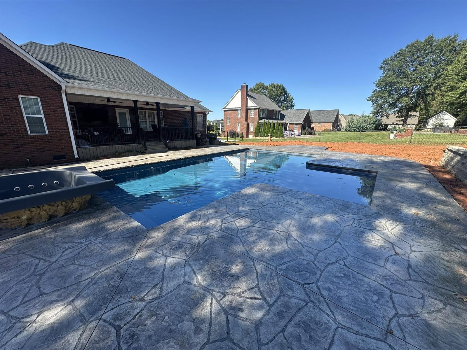Custom in-ground pool with stone retaining wall and mountain views at dusk