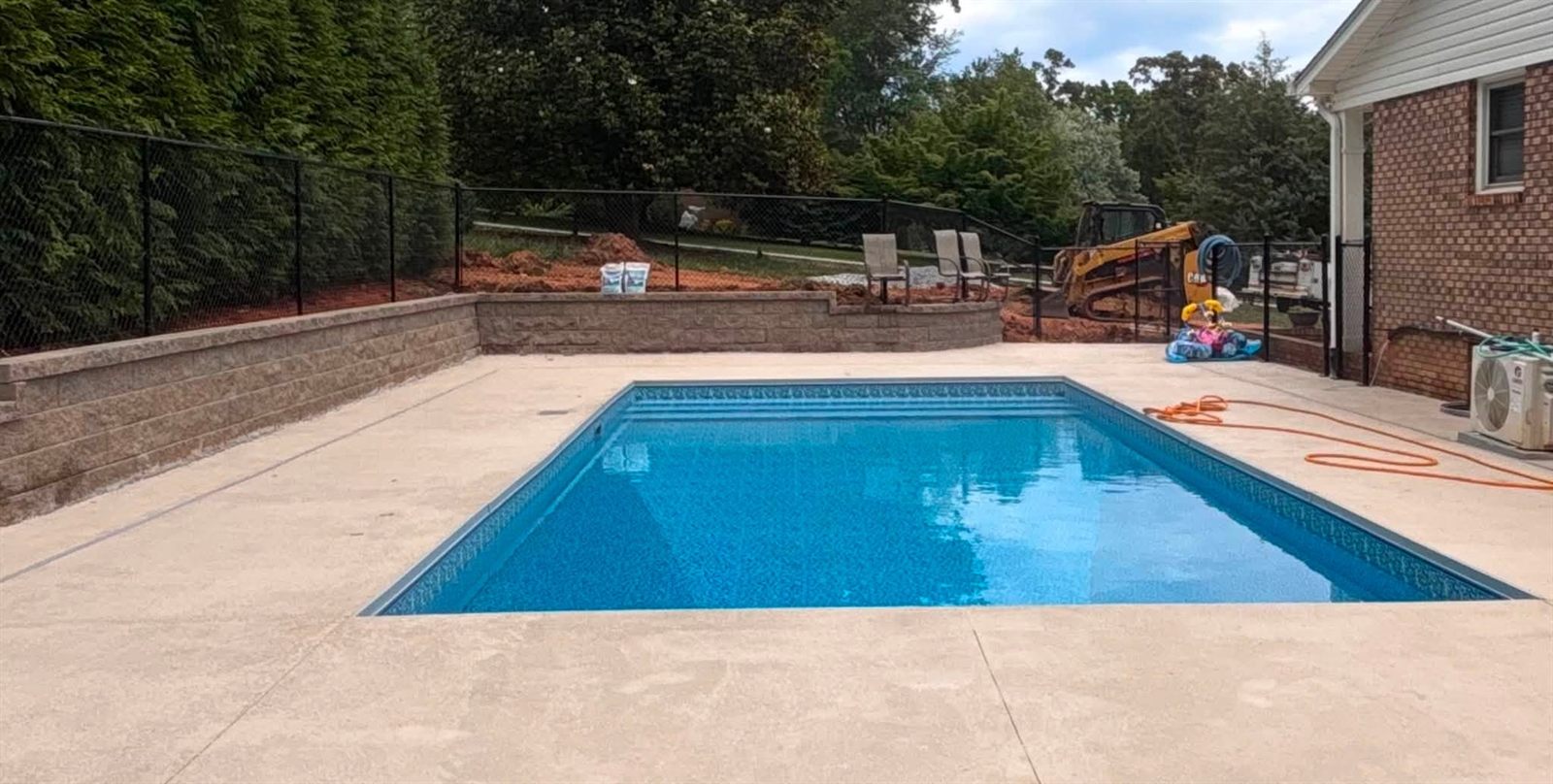 Finished pool with a block retaining wall holding the grade at the edge of the deck